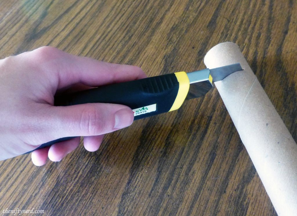 using a utility knife to cut a cardboard tube