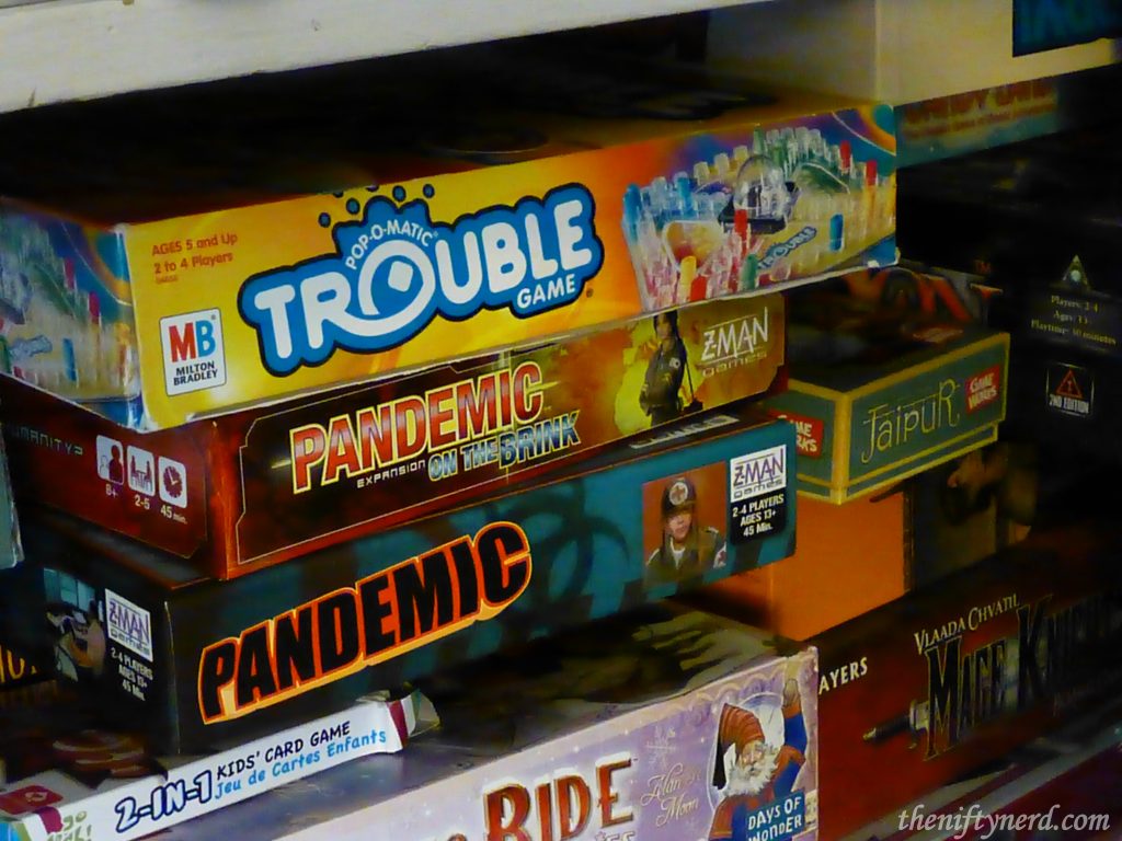 Closet shelf full of board games like Trouble and Pandemic